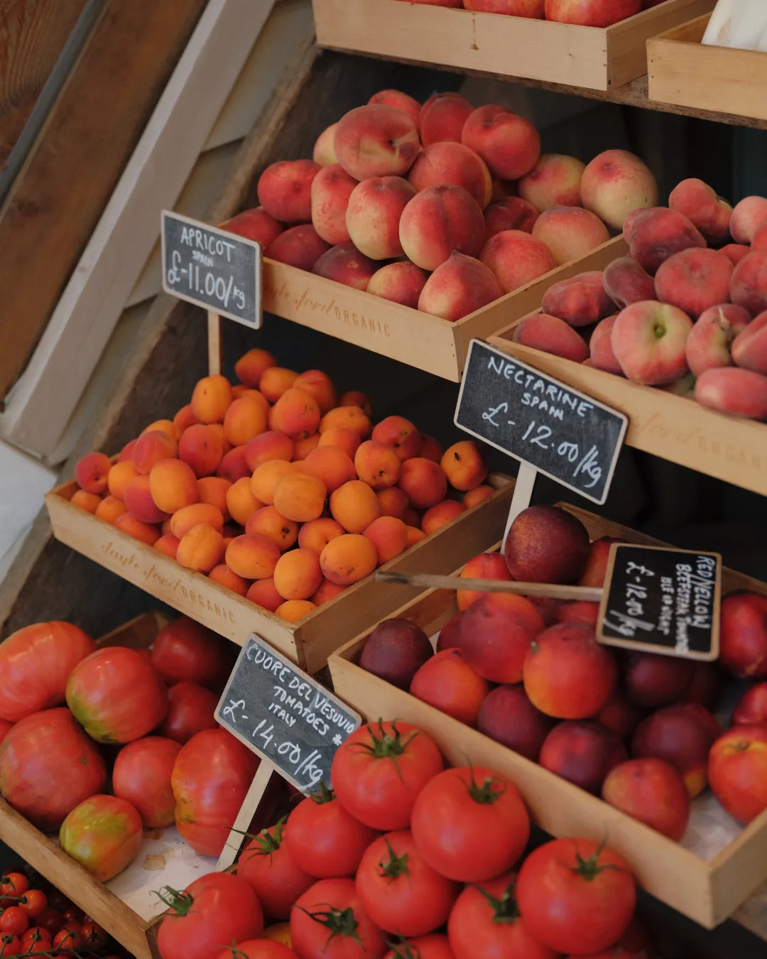 Apricots, peaches and tomatoes with handwritten price boards