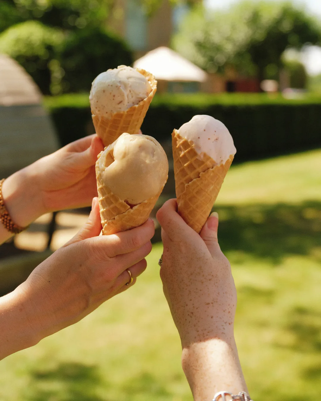 Three ice cream cones held up in the sunshine