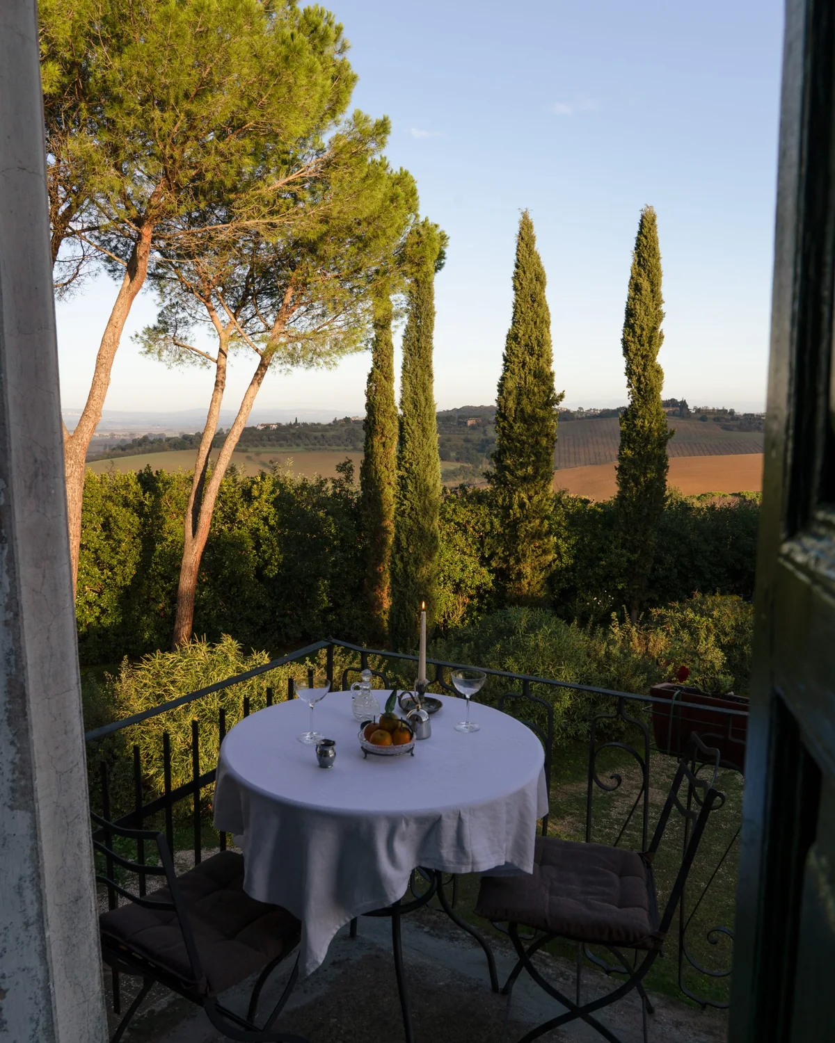 A table for two on a terrace, looking out over cypresses and Tuscan farmland
